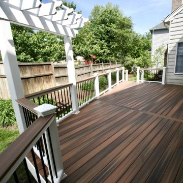 Backyard deck with pergola, black balusters, and wood-look decking