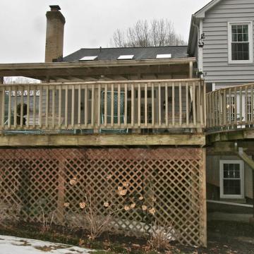 Aging elevated wood deck with lattice skirting behind a house