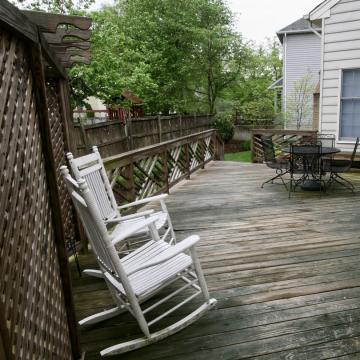 Weathered wood backyard deck with lattice screen, rocking chairs, and patio set