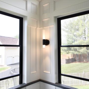 Black-framed corner windows with paneled walls and modern sconce