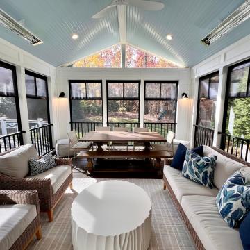 Bright three season room with dining table and wicker seating