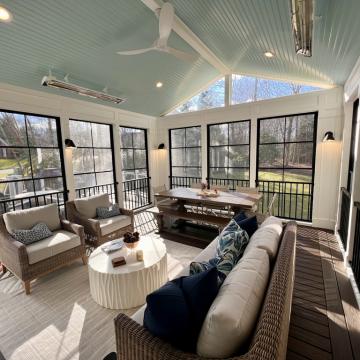 Bright three season room with screened walls, seating, and dining table