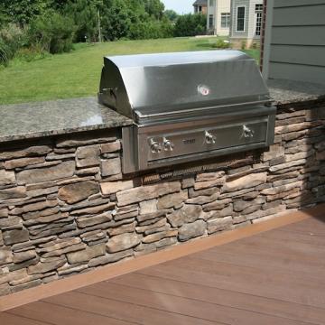 Built-in stainless grill with stone veneer base and granite counters