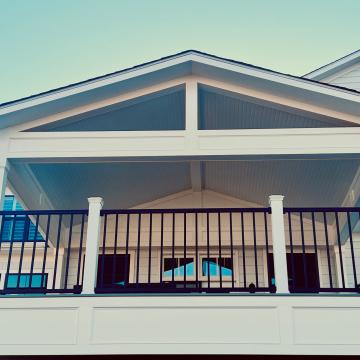 Covered open-air porch with gabled roof and black railing