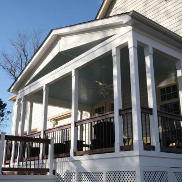 Covered open air porch with white columns and dark railing