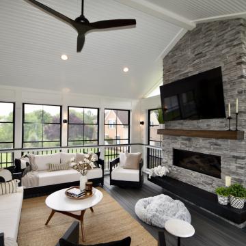 Covered patio lounge with stacked stone fireplace and mounted TV