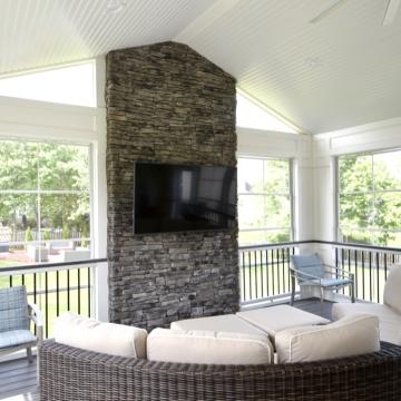 Covered patio seating area with stone fireplace and mounted TV