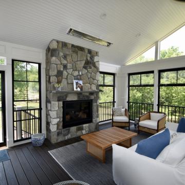 Covered patio with stone fireplace, seating area, and large windows