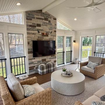 Covered patio sunroom with tall stone fireplace and seating area