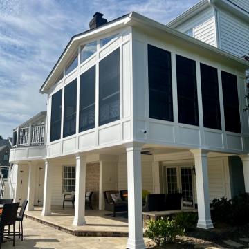 Elevated white three season room with screened windows and gabled roof