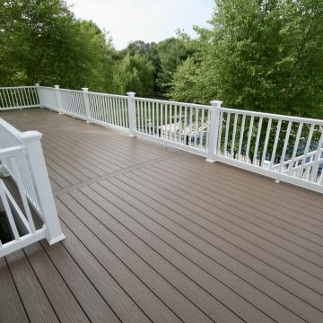 Large composite deck with white railings overlooking a wooded backyard