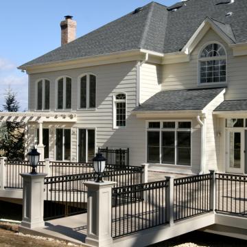 Large elevated backyard deck with black railings and white pergola