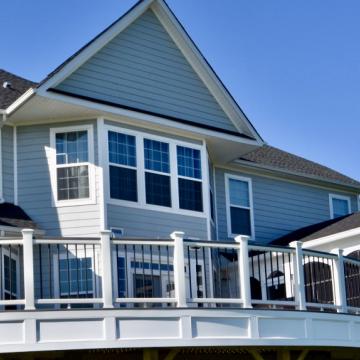 Large elevated white deck with black railings behind house