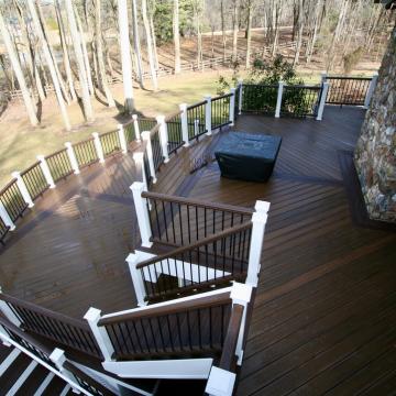 Multi-level wood deck with white railings beside stone exterior