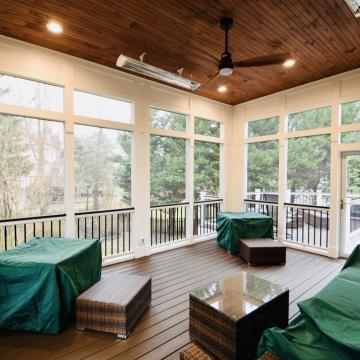Screen porch interior with wood ceiling, large windows, and covered furniture