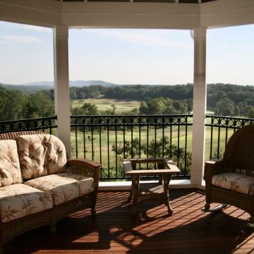 Screen porch seating area overlooking open fields and distant hills