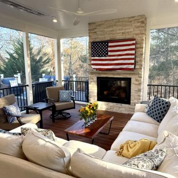 Screen porch seating area with stone fireplace and large windows