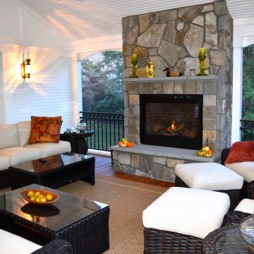 Screen porch seating area with stone fireplace and wicker furniture