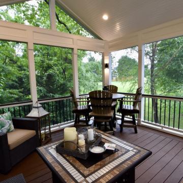 Screen porch with vaulted ceiling, dining set, and wooded views