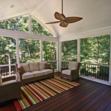 Screen porch with vaulted ceiling, ceiling fan, and wicker seating