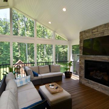 Screen porch with vaulted ceiling, stone fireplace, and seating area