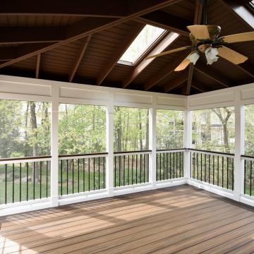 Screen porch interior with vaulted wood ceiling, skylights, and fan