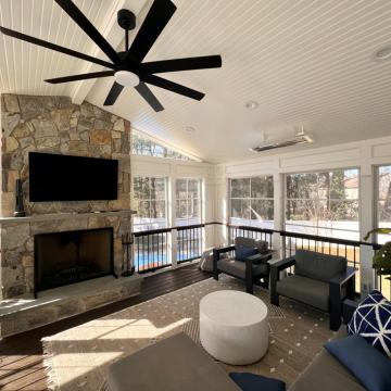 Screened patio with stone fireplace, TV, and seating area