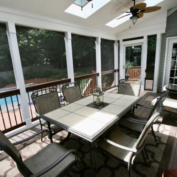 Screened porch with dining table, skylights, and pool views