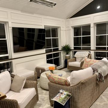 Screened porch seating area with TV, heater, and wicker furniture