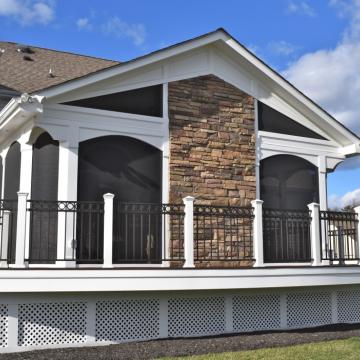 Screened porch with stone fireplace wall and elevated deck railing