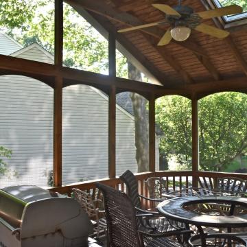 Screened porch with vaulted wood ceiling, skylight, grill, and dining set