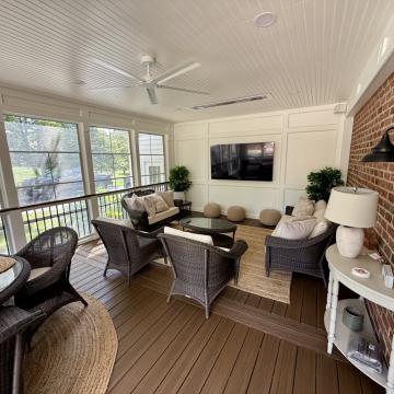 Screened porch with wicker seating, brick wall, and TV