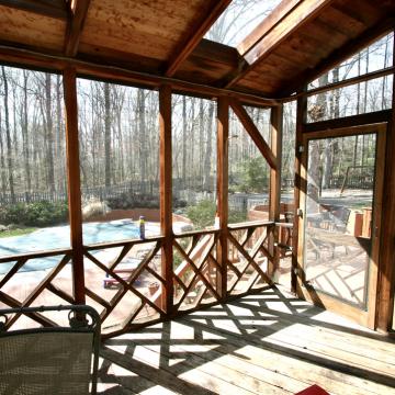 Screened porch with wood framing overlooking deck and covered pool