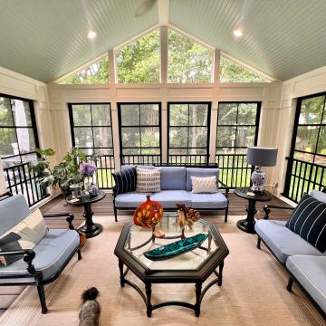 Screened three-season room with blue seating and vaulted beadboard ceiling