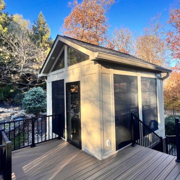 Screened three season room on elevated deck with wooded backdrop