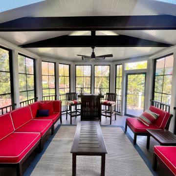 Screened three season room with red seating and black beams