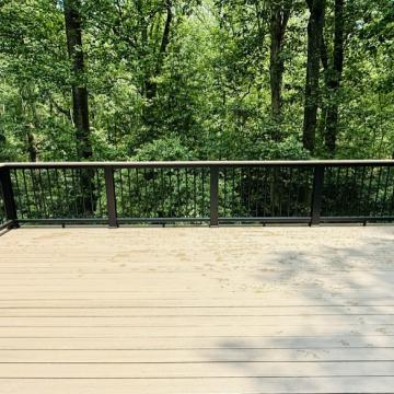 Spacious composite deck with dark metal railing overlooking wooded backyard
