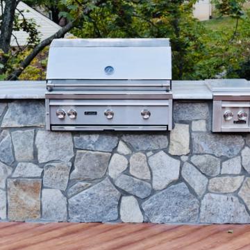 Stone outdoor kitchen island with stainless grill and side burner