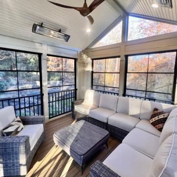 Sunlit three season room with wicker seating and tall windows