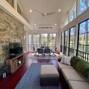 Three season room with stone wall, tall windows, and seating