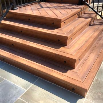Tiered wooden deck steps with black railings and recessed lights