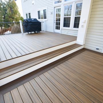 Two-level composite deck with black railing and grill near house
