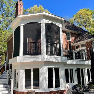 Two-story screened porch addition on brick home with deck