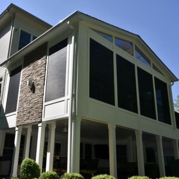 Two-story screened porch with gabled roof and stone accent wall