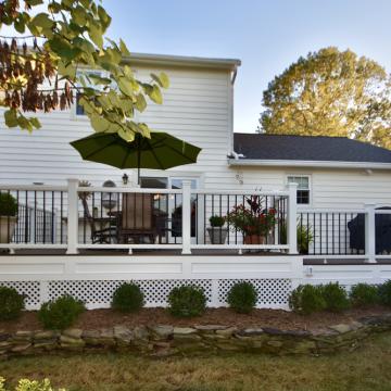 White backyard deck with black railing, stairs, and patio umbrella