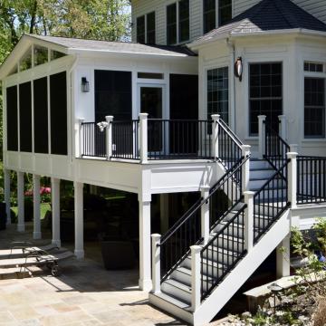 White elevated screen porch with black railings and stairs