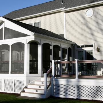 White gabled screen porch connected to an elevated backyard deck