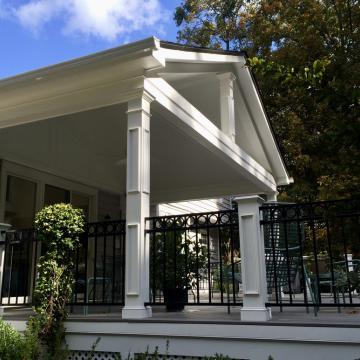 White open-air porch with black railing and seating area