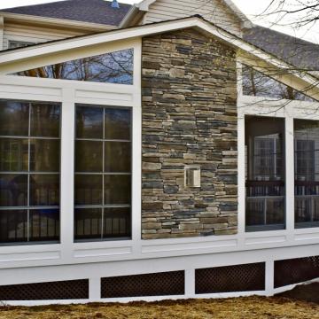 White screened porch exterior with stone fireplace chimney wall