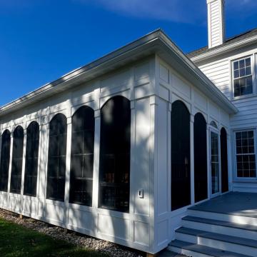 White three season room with arched screened windows and steps